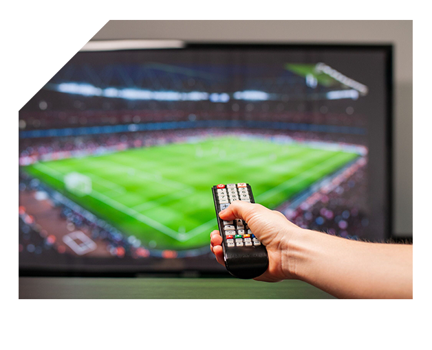 Téléspectateur qui règle sa télécommande devant un stade de football diffusé en IPTV France 4K